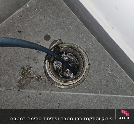 ניקוז מים עם צינור כחול ברצפה אפורה